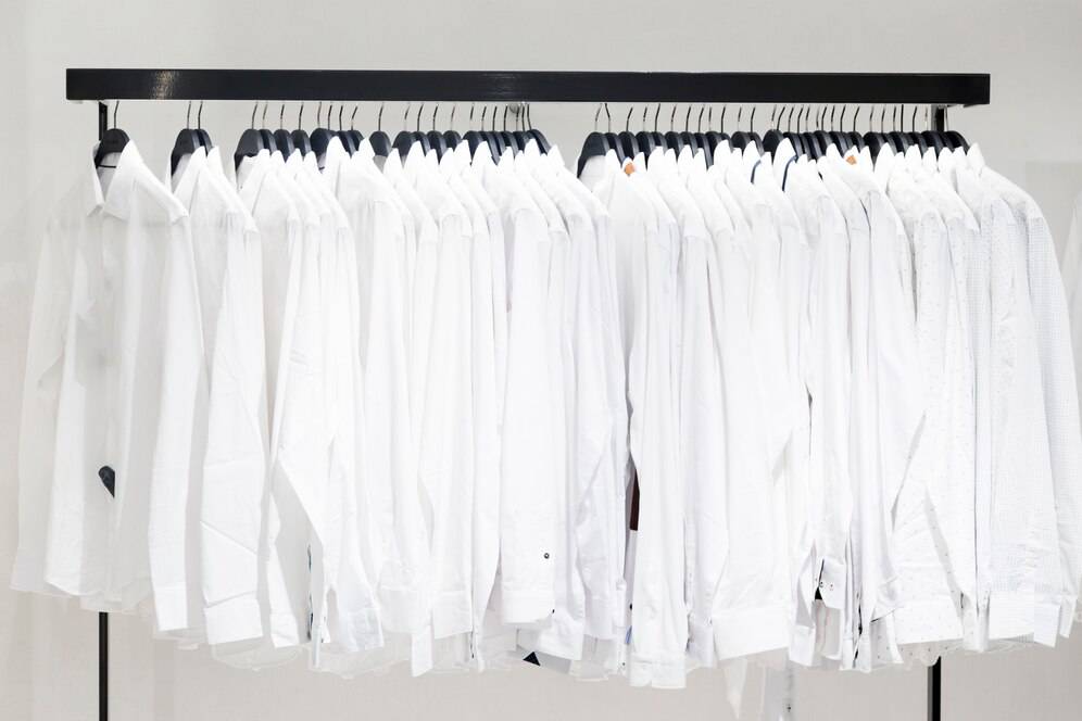 A clothing rack displaying a row of neatly arranged white shirts, showcasing various styles and textures.