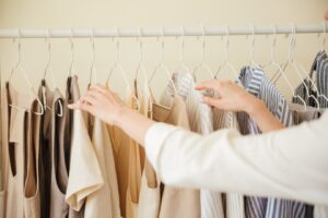 A women maintain her wardrobe by the hand and arrange the cloth also.