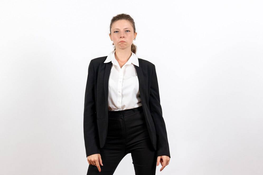 A confident individual poses in a tailored black suit and white shirt against a plain white background.